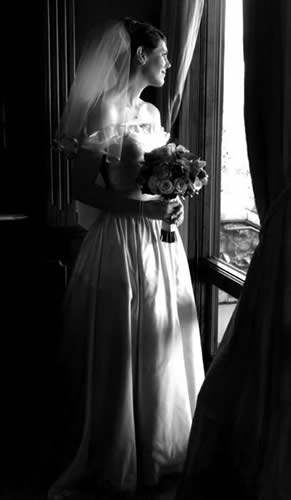 Bride in a custom Carole Kenney Design gown by a window